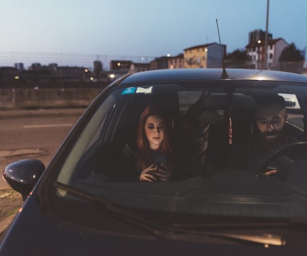 Couple in car at night using smartphone